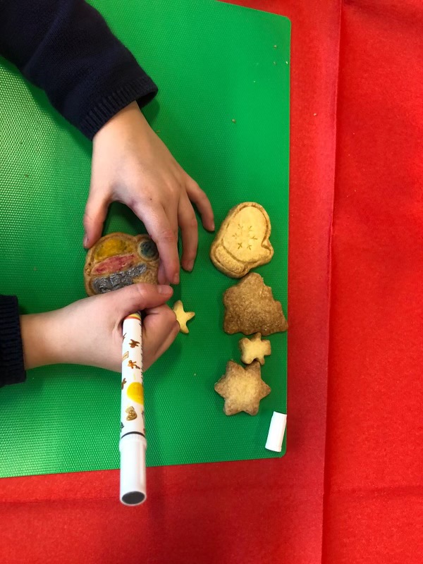 Mains d'enfant décorant un sablé de Noël au feutre alimentaire lors d'un atelier Anni-Zen